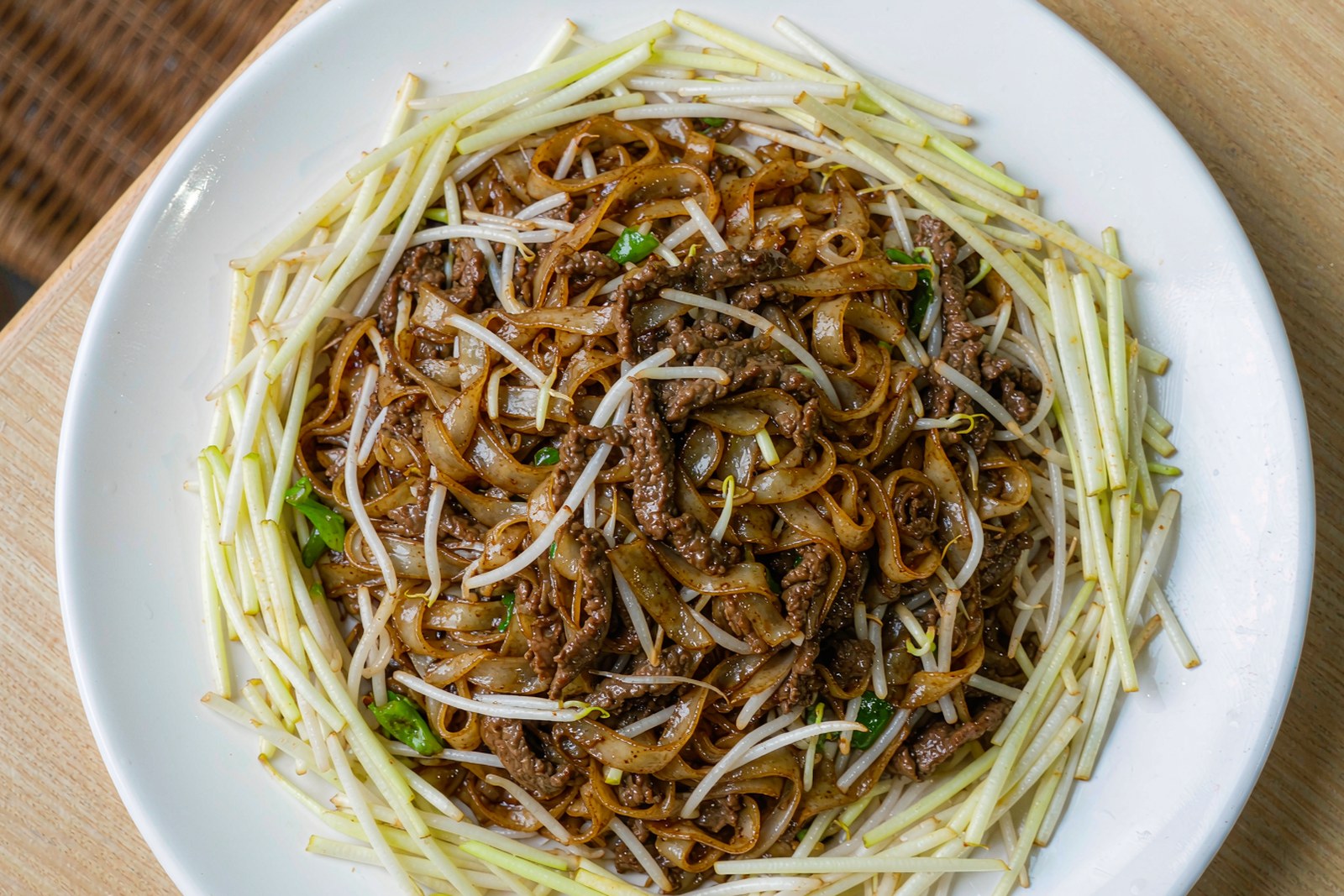 A plate of dry-fried beef ho fun with bean sprouts and yellow chives
