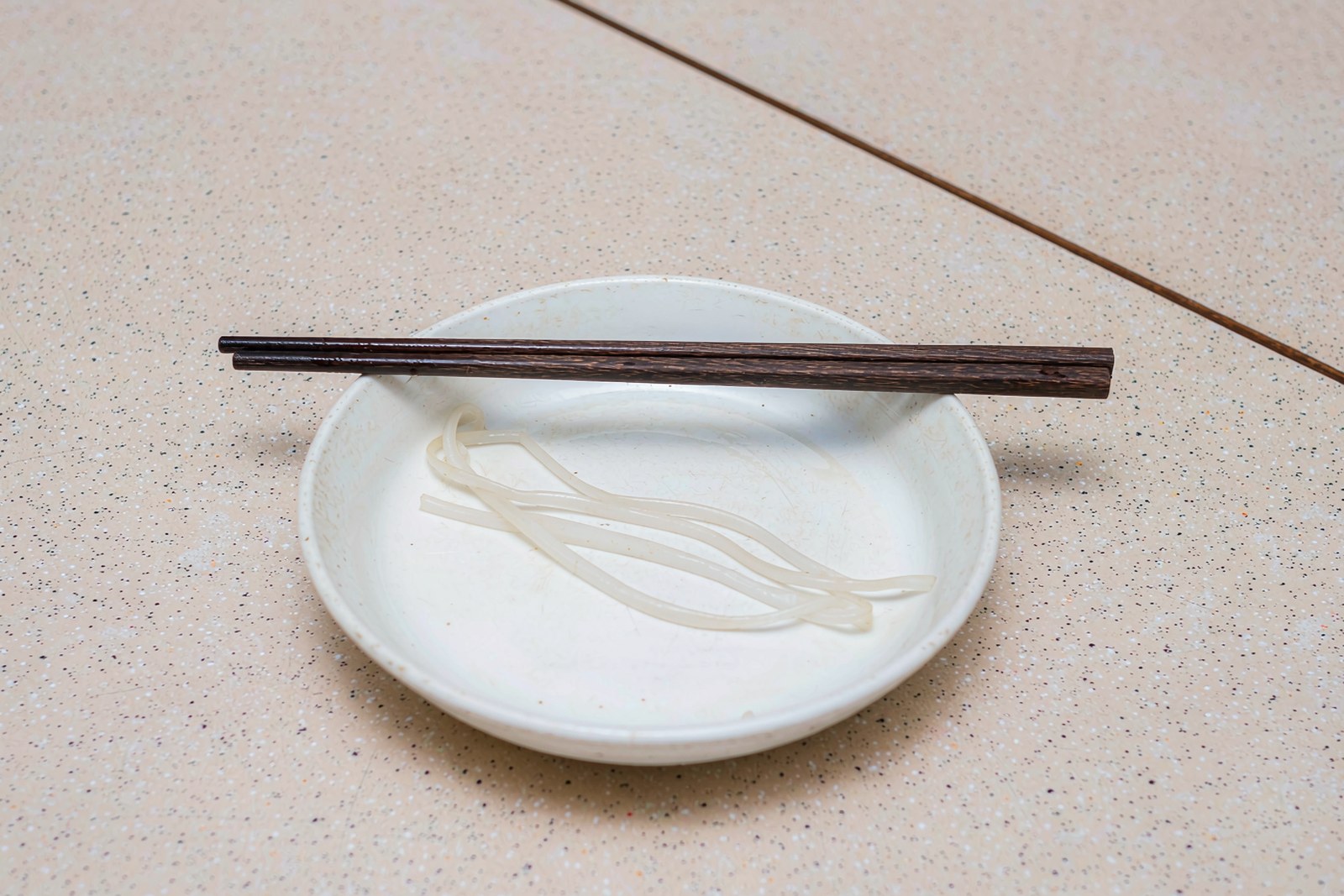 An empty plate with a few rice noodles and no pool of oil left in the bottom