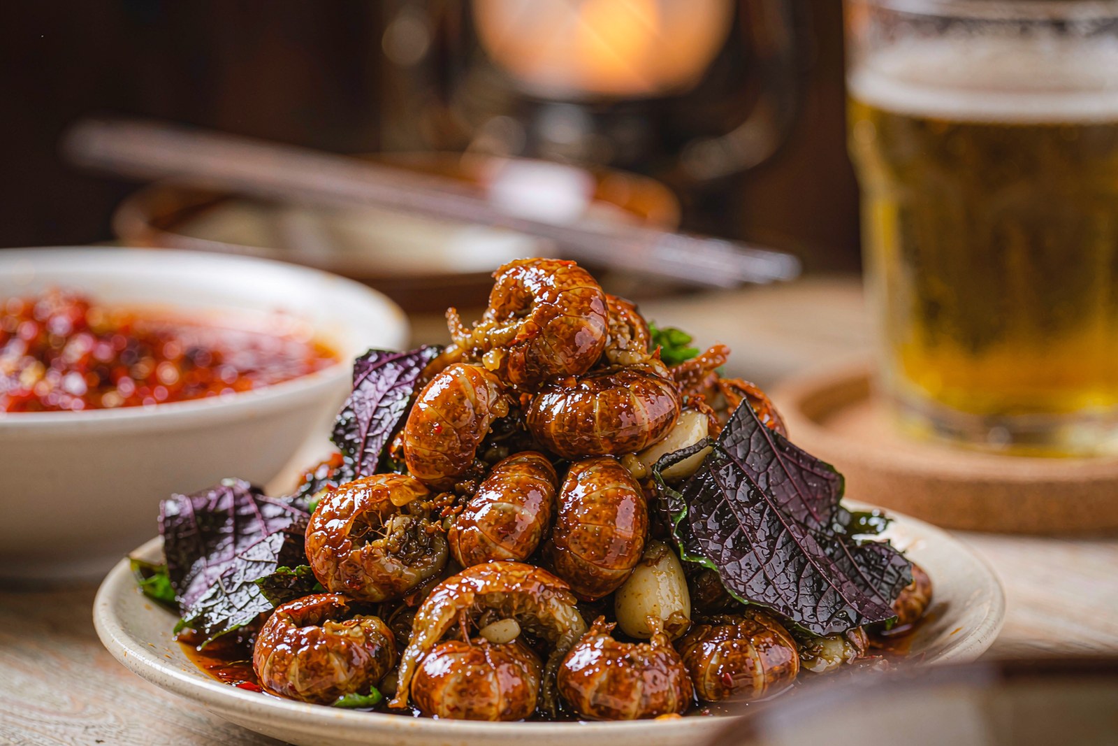 Close-up of crayfish tails coated in dark chilli sauce with perilla leaves