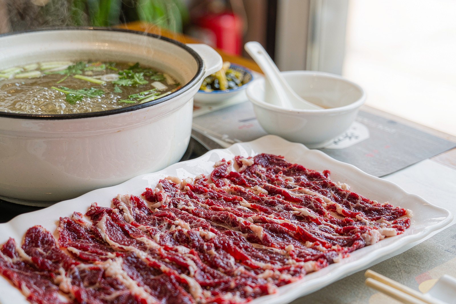 Raw marbled beef slices with a boiling broth pot