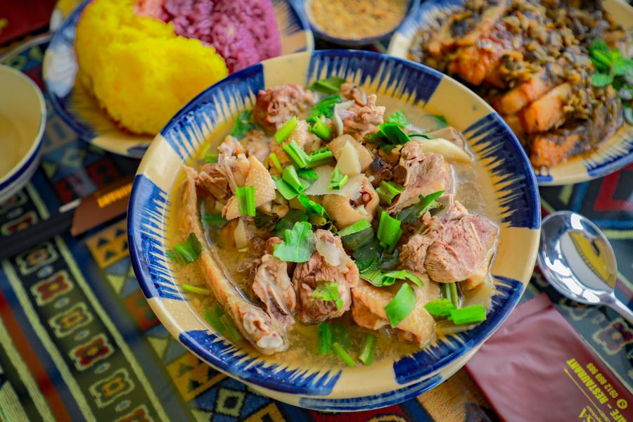 A steaming bowl of clear duck broth with vermicelli and dark cubes of duck blood