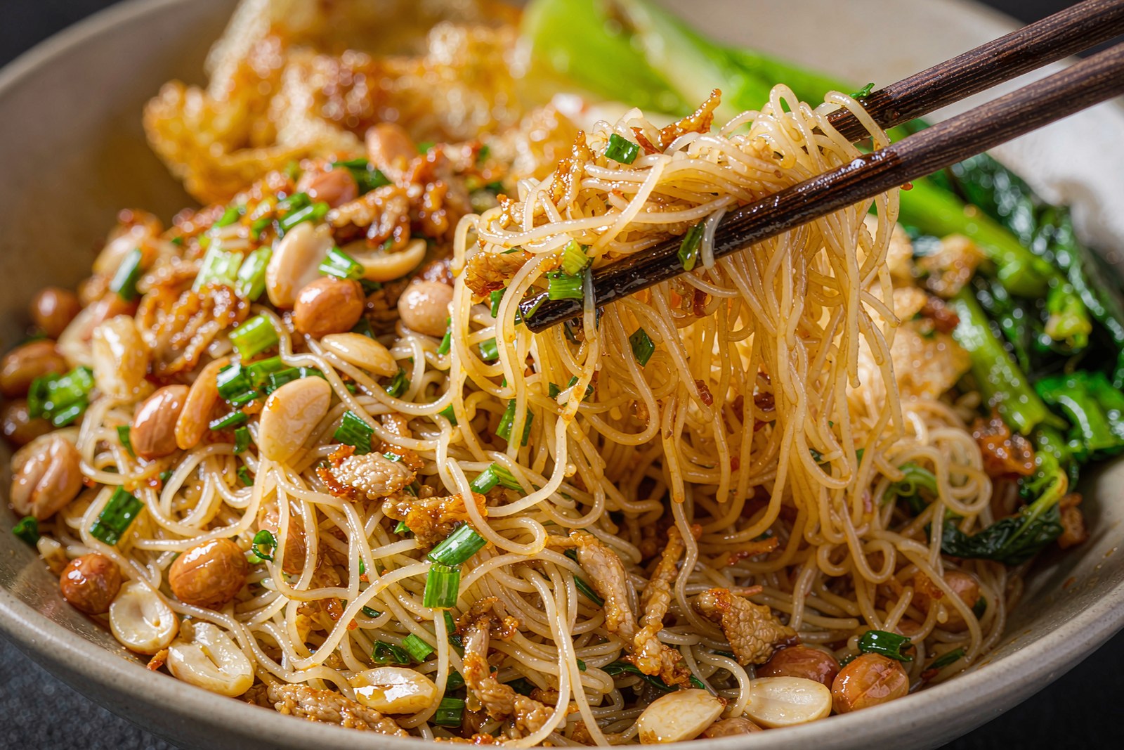 Fine Hainan fen noodles being mixed through a glossy amber sauce