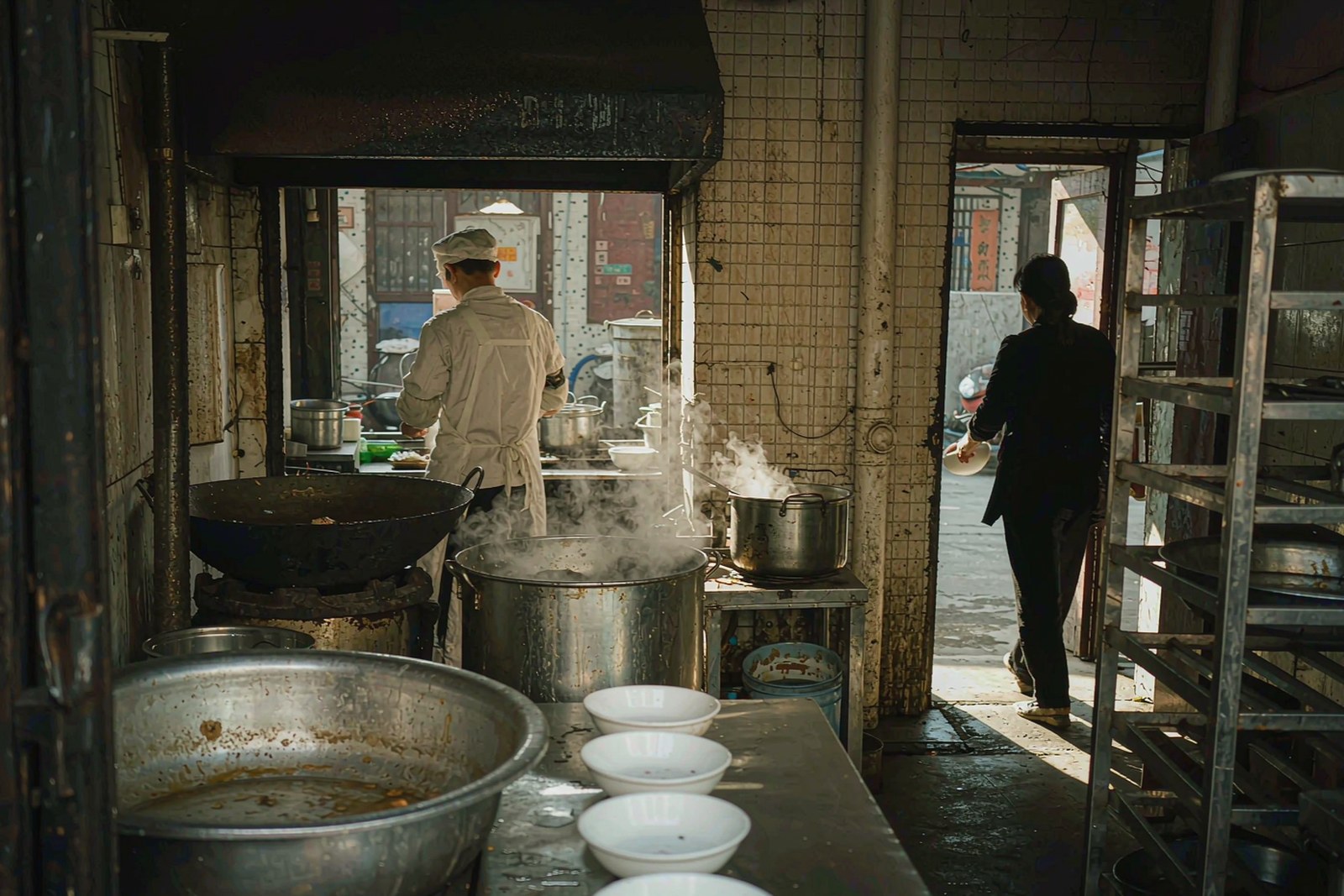 Morning at a north-gate noodle shop, bowls on the counter and steam in the doorway