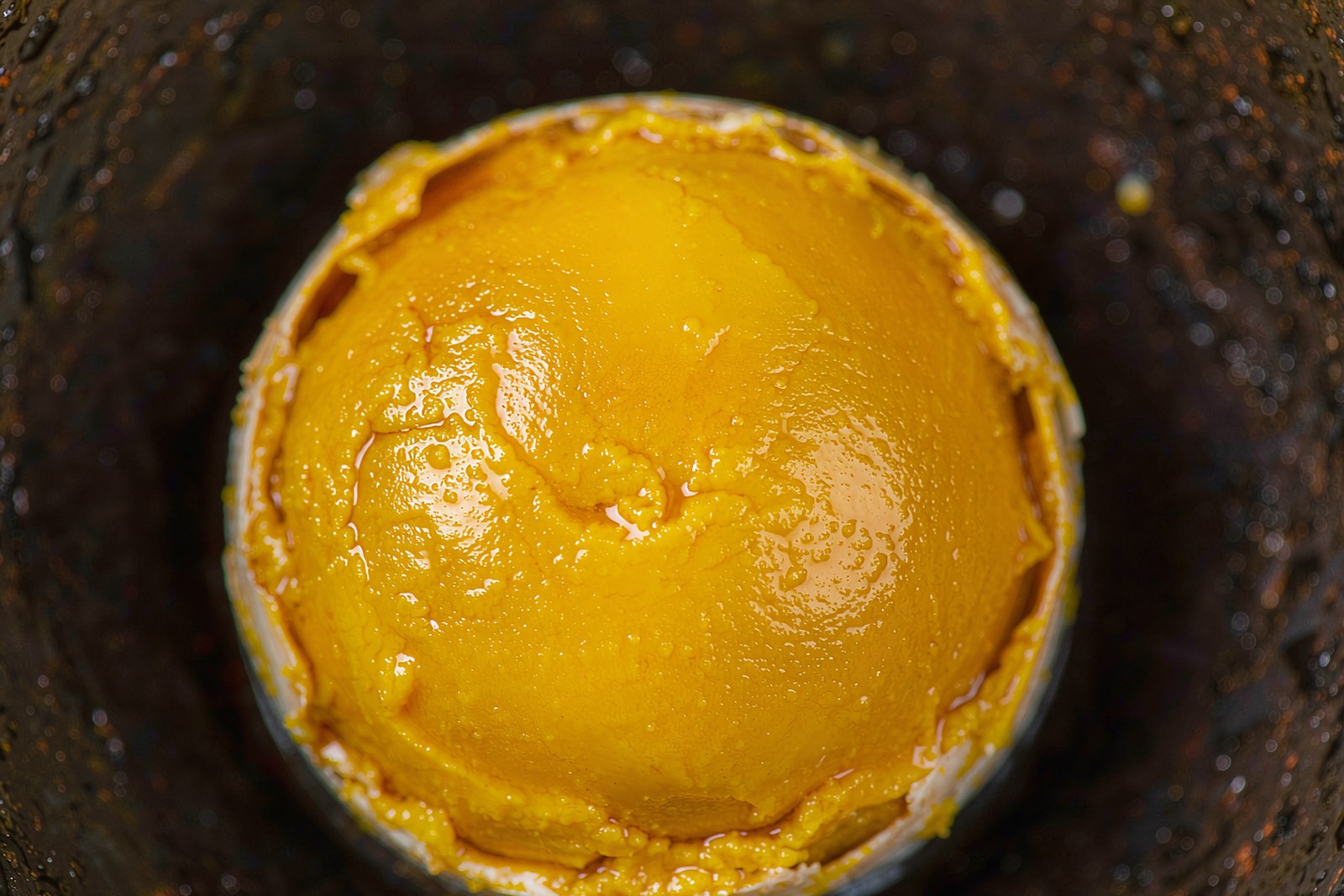 A deep golden mass of crab roe inside an opened Hele shell