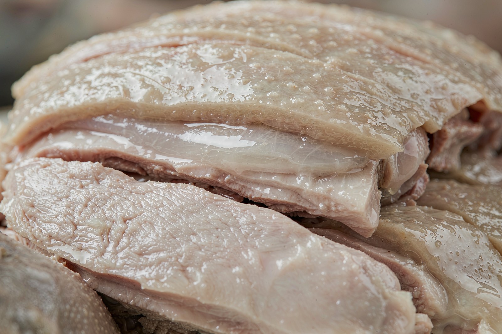 A close view of sliced white-cut duck showing pale skin and a glossy fat layer