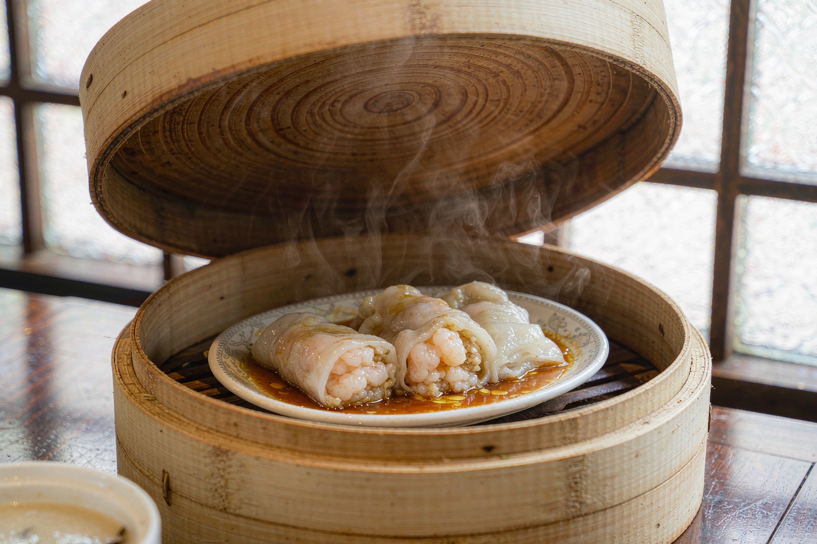 A bamboo steamer revealing translucent shrimp rice rolls