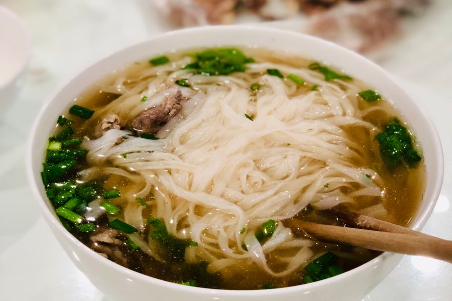 A bowl of rice noodles floating in pale broth