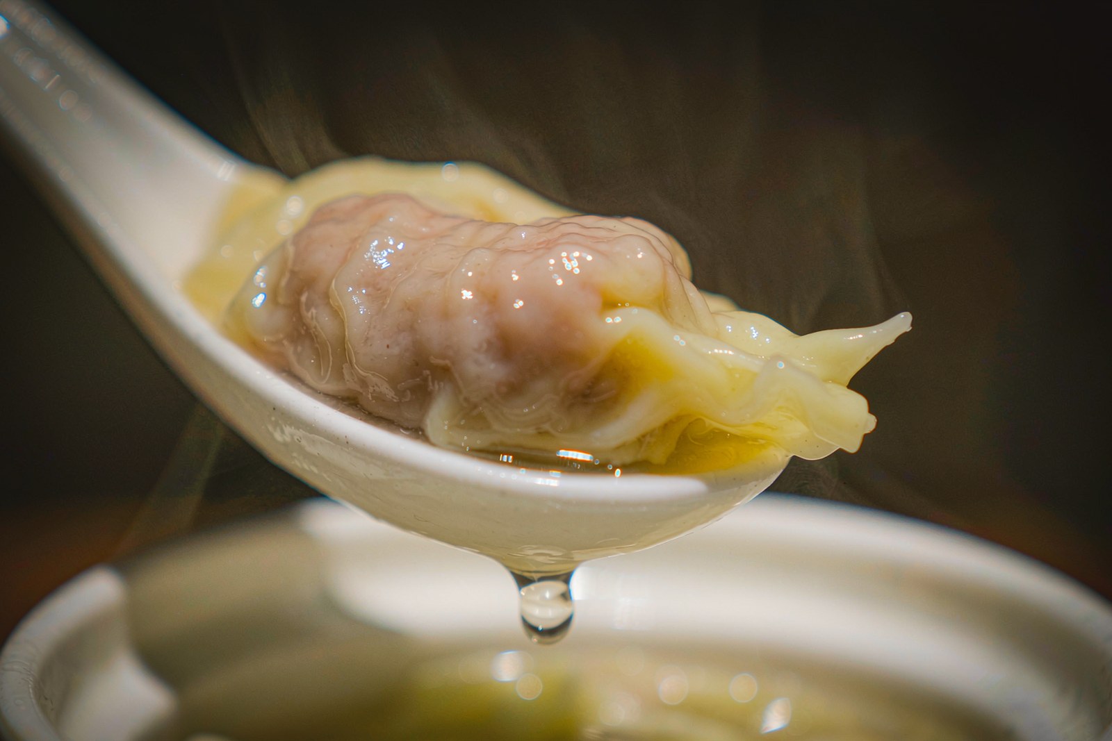A bowl of thin-skinned wontons with swallow-tail folds in clear stock