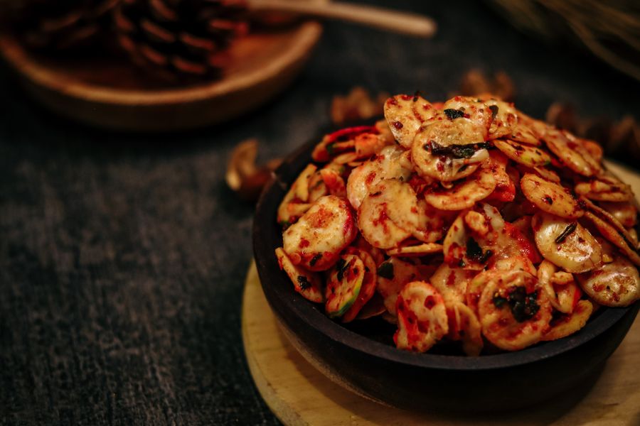 A single lacquered rice cake lifted on chopsticks, syrup trailing
