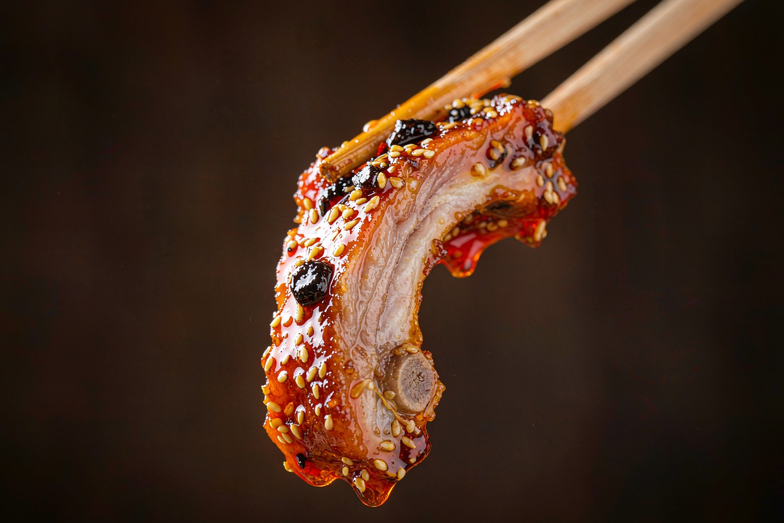 A single glazed Tengqiao rib held with chopsticks, honey glaze dripping