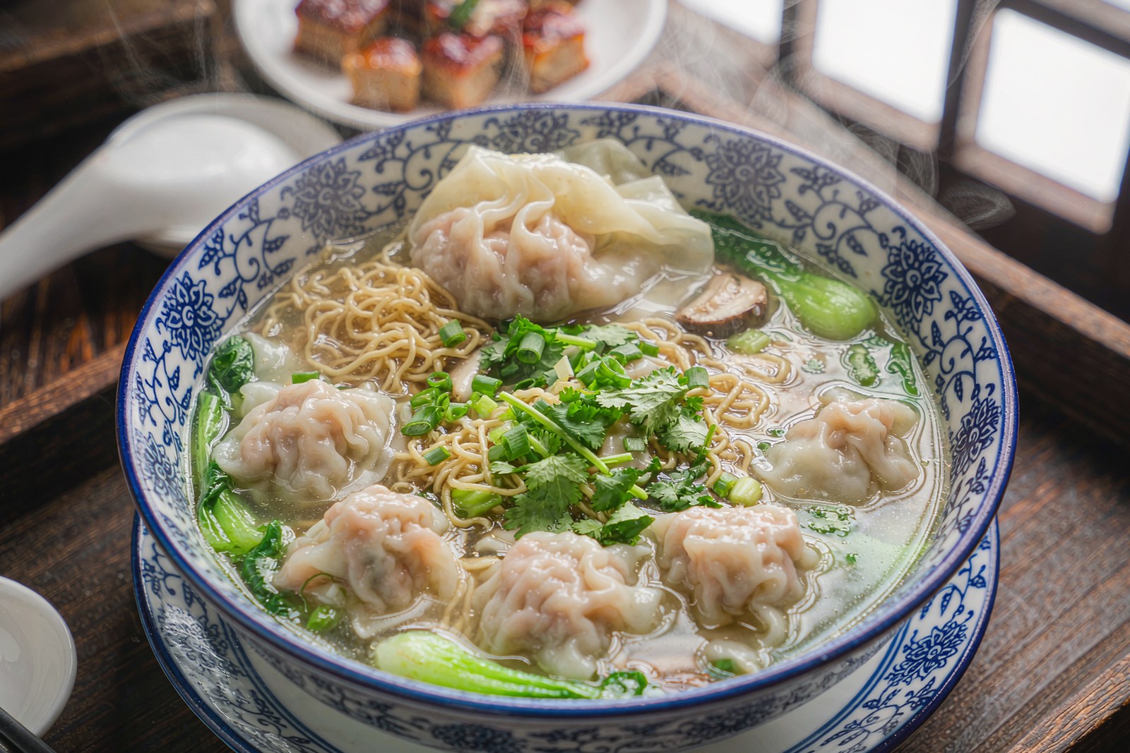 A bowl of wonton noodles in clear broth