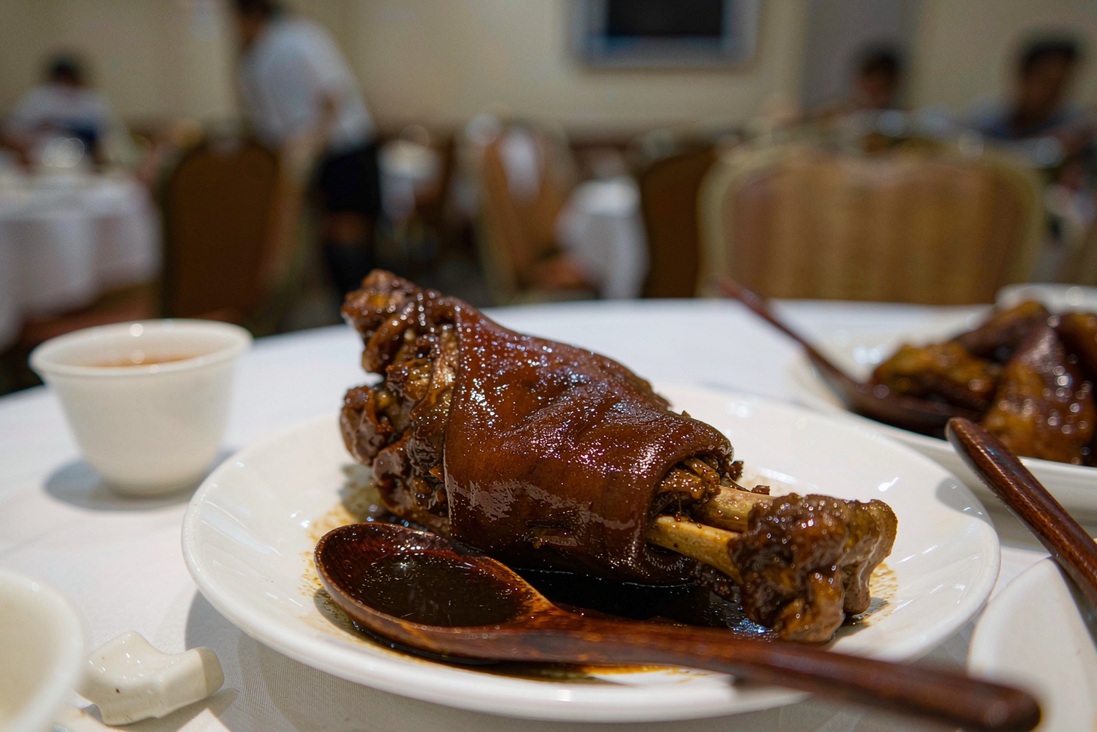 A dark, glossy braised pork hock served whole at the table