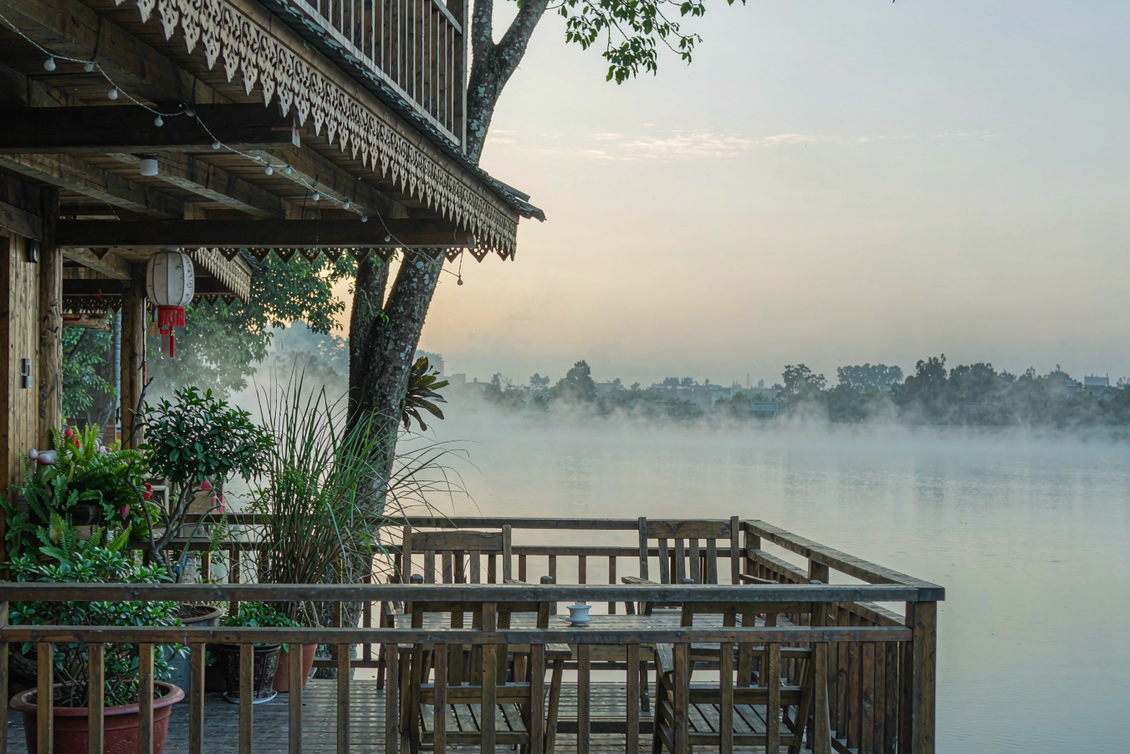 A modest riverside guesthouse terrace looking out over the lake at first light