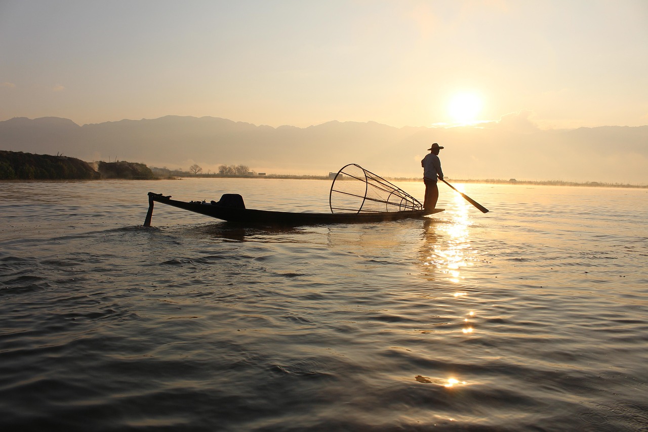 A fisherman casting a net in the shallow water at dawn