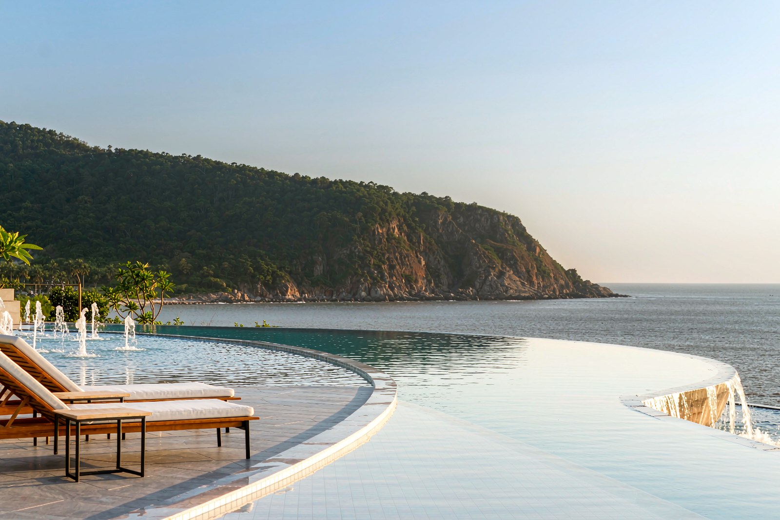 A resort infinity pool overlooking the bay and its dark forest edge