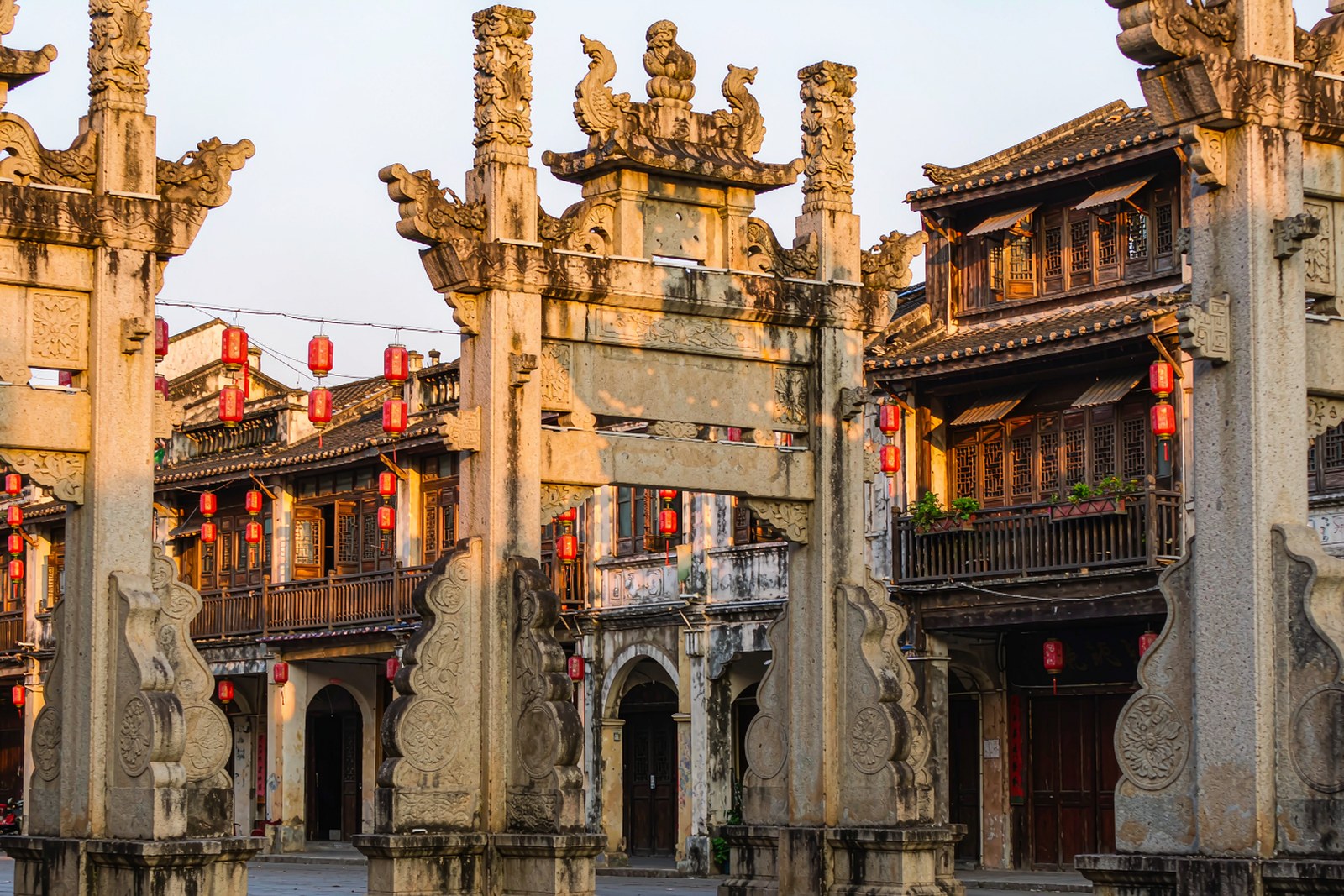 Row of stone memorial arches and arcaded shophouses along an old town street