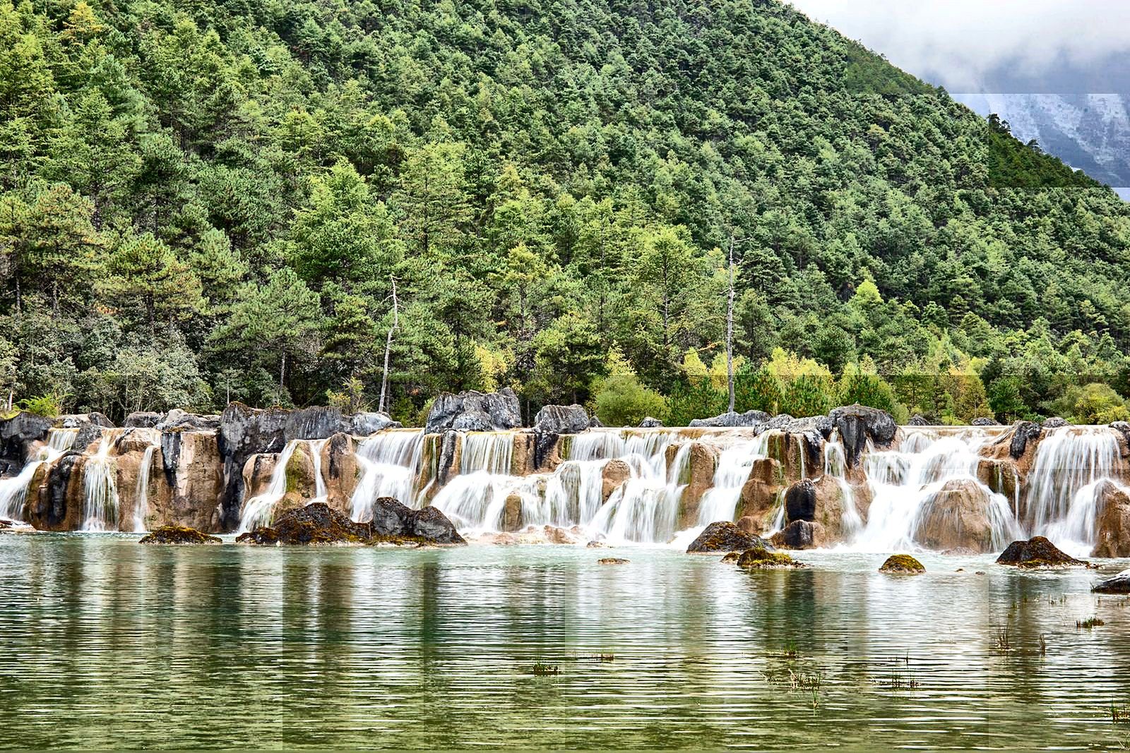 A gentle waterfall falling among rocks and trees at Dinghu Mountain