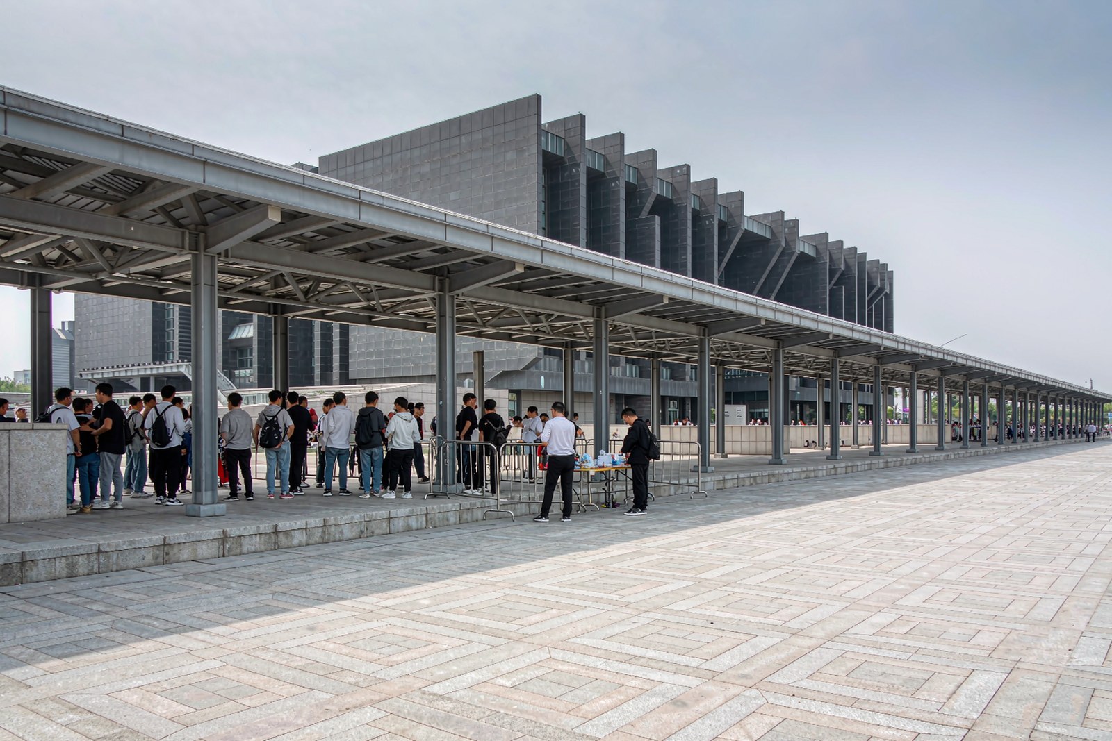 The museum’s stepped exterior above a plaza, visitors queuing under a covered walkway