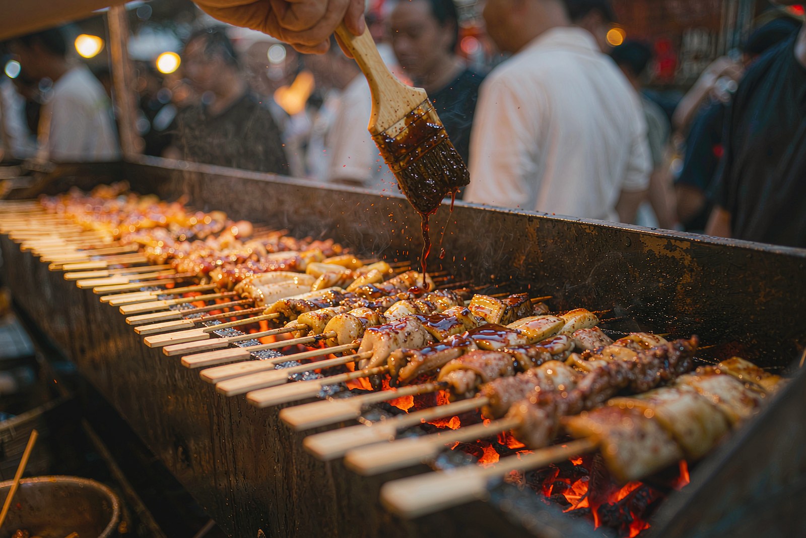 Skewers grilling over a long charcoal trough at a street stall
