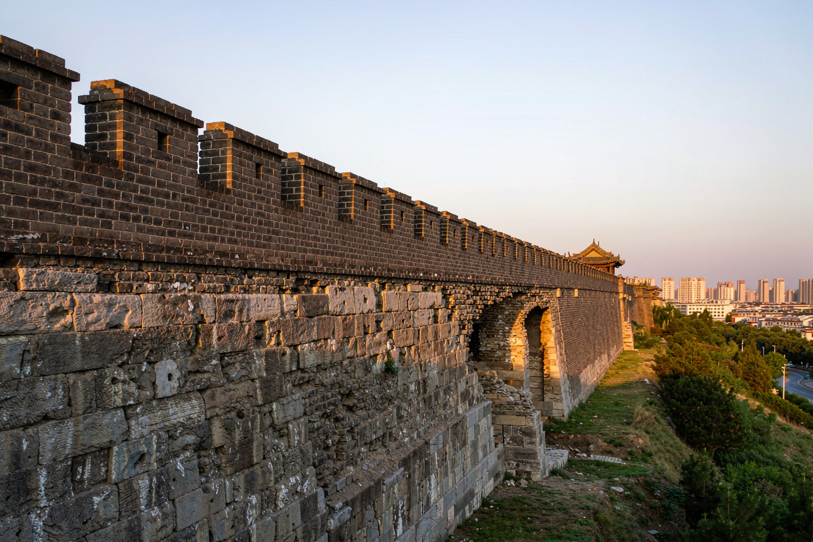 The crenellated grey city wall running along the top of the hill