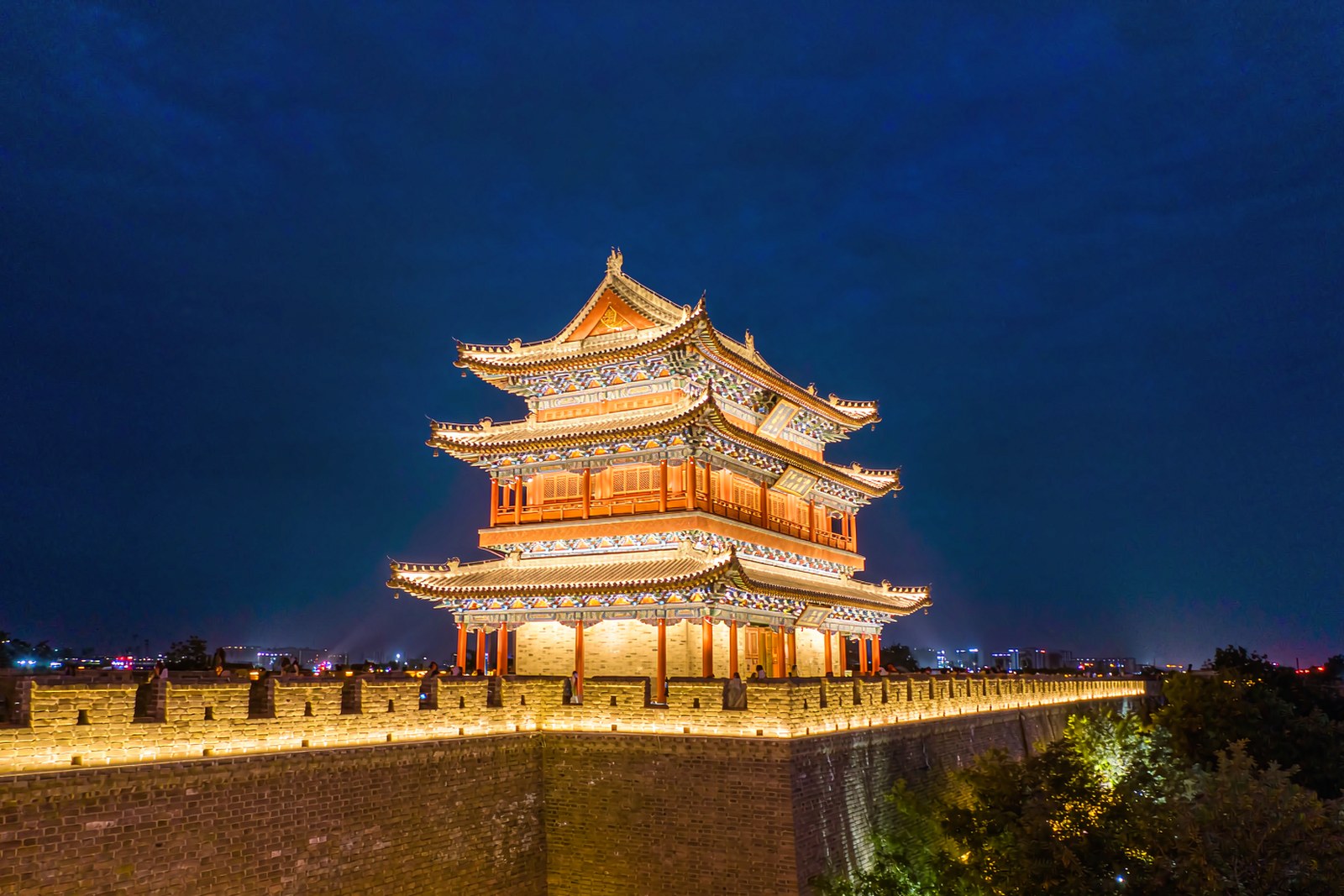 A three-storey pavilion with upturned eaves lit against the evening sky